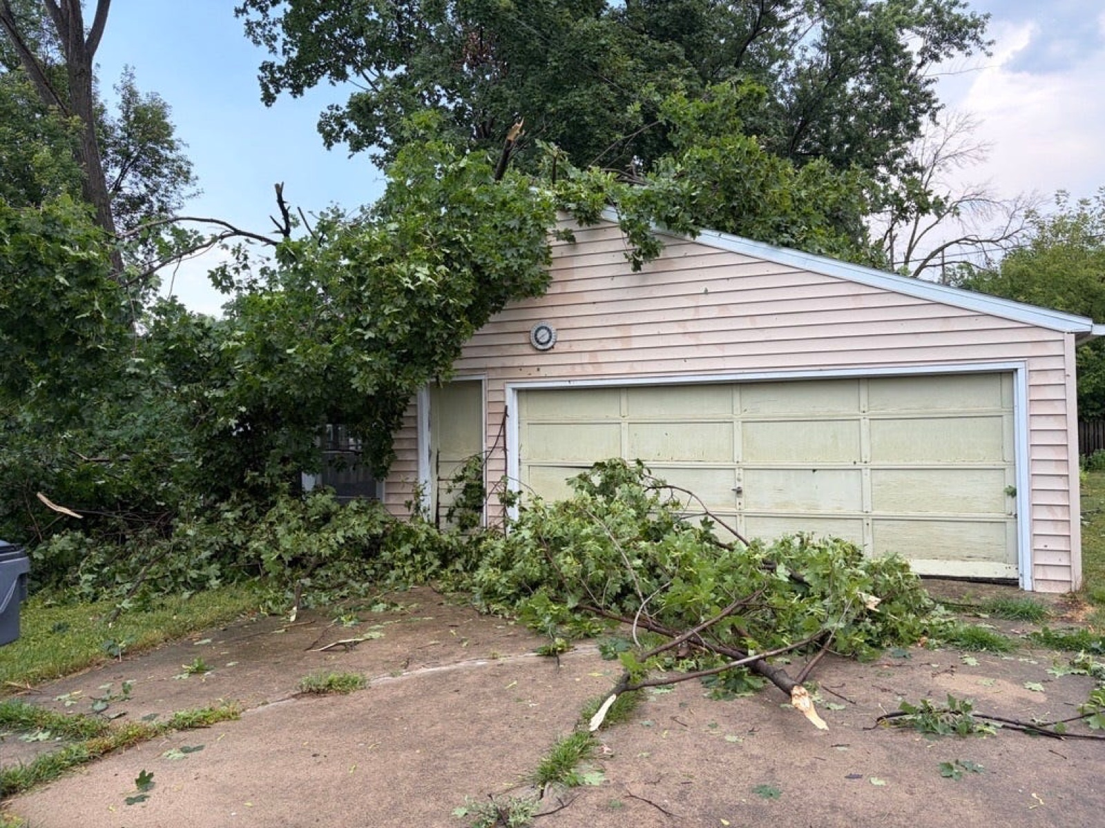 A tree resting on a garage in the 500 block of Chestnut Street in Neenah, Wisconsin after the July 27, 2026 tornado