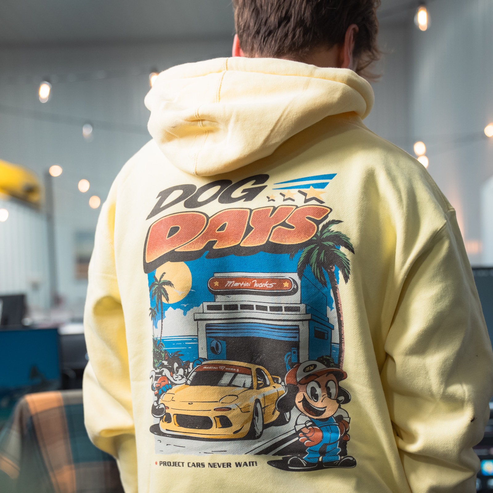 The back of a butter yellow Dog Days hoodie with the MartiniWorks diner graphic