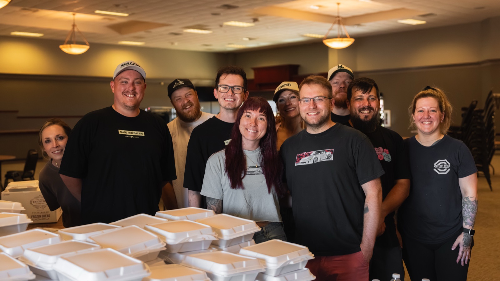 The MartiniWorks team posing behind stacks of packed relief meals